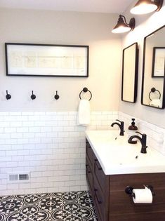 a bathroom with black and white tile flooring, two sinks and three mirrors on the wall