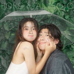 two people standing under an umbrella in front of green plants and trees with the words hong mai toh on it