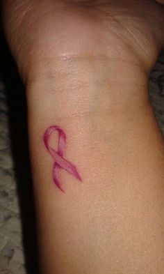 a small pink ribbon tattoo on the wrist