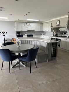 a kitchen with a table, chairs and an island in the middle that has white cabinets