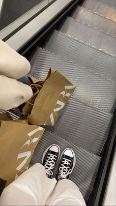 someone is standing on an escalator with their feet up