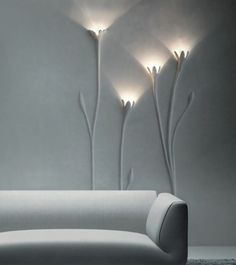 a white couch sitting in front of a wall with three lights on top of it