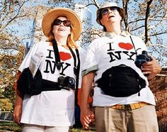 two people wearing t - shirts that say i love new york and one is holding a camera