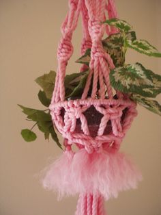 a potted plant with pink yarn hanging from it's sides and green leaves on the other side