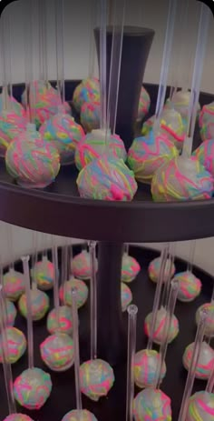 three tiered tray filled with cake pops covered in multicolored icing