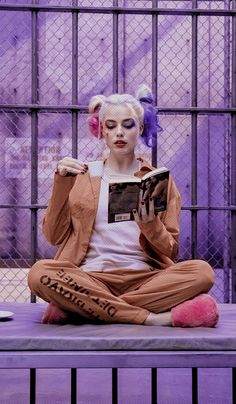 a woman sitting on top of a purple bench next to a caged in area