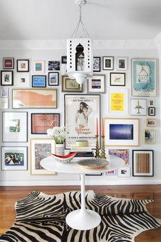 a dining room with pictures on the wall and a zebra rug in front of it