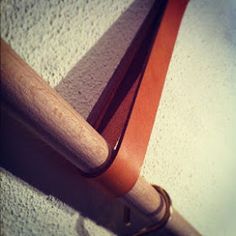 a baseball bat leaning against the wall with a leather strap hanging from it's end