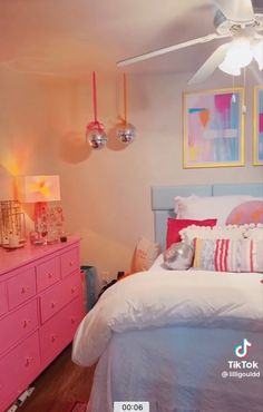 a bed room with a neatly made bed and pink dressers next to each other