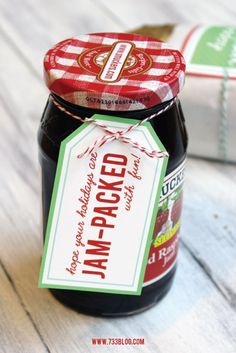 a jar of jam sitting on top of a wooden table next to a wrapped package