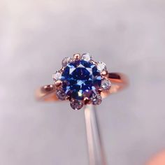 a ring with a blue and white diamond surrounded by smaller round cut diamonds on top