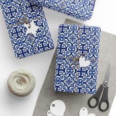 blue and white wrapping paper on top of a table with scissors, twine and yarn