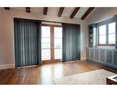 an empty living room with wood floors and blue curtains