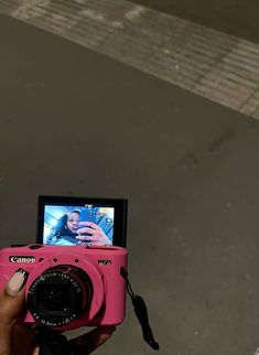 a person holding a pink camera taking a picture