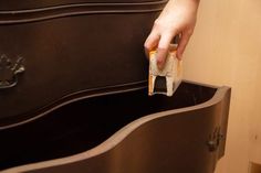 a person is holding something in their hand near a drawer that has drawers on it