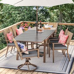 an outdoor table and chairs on a deck with an umbrella over the dining room table