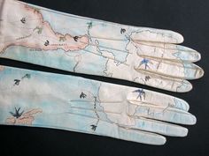 two white gloves with designs on them sitting next to each other and one has blue birds flying over the map