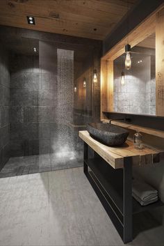 a bathroom with a sink, mirror and shower stall in the corner is lit by pendant lights