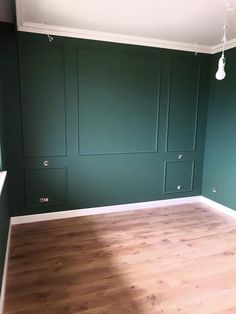 an empty room with green walls and wood flooring in the center is painted dark green