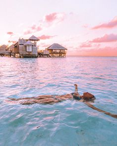 a woman floating in the ocean next to some houses on stilfets and water