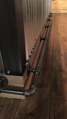 a wooden floor with metal pipes on the side and wood floors in front of it