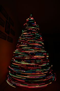 a christmas tree is lit up in the dark with colorful lights on it's sides