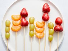 fruit skewers are arranged on a white plate