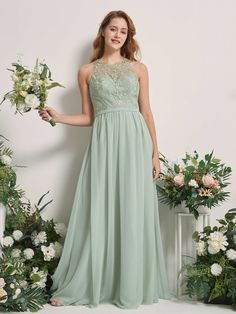 a woman standing in front of flowers wearing a long green dress with lace and chiffon