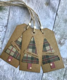 three tags with plaid designs on them hanging from twine string against a wooden background