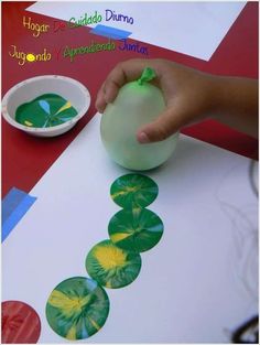 a child's hand is holding a green ball over a paper plate with four leaf designs on it