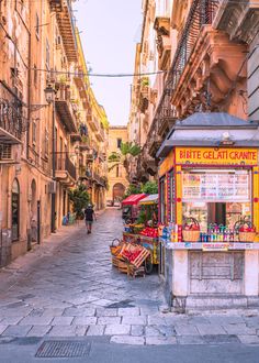 an old street with people walking down it and shops on the sidewalk in front of buildings