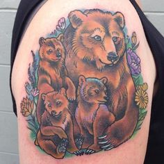 a bear family tattoo on the back of a woman's shoulder with flowers around it