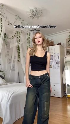 a woman standing in front of a bed wearing high waisted jeans and crop top