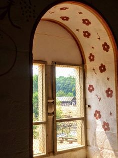 an arched window with flowers painted on the wall and in between it is a bench