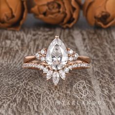 a rose gold ring with a pear shaped diamond surrounded by smaller round brilliant cut diamonds