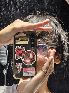 a woman taking a selfie with her cell phone in front of her face and some stickers on it