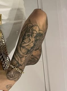 a man with tattoos on his arm holding a cell phone in his hand and wearing a chain around his wrist