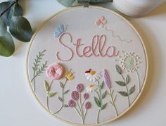 a embroidery kit with flowers and the word stella on it next to a glass of milk