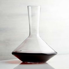 a large glass vase sitting on top of a white table next to a black bowl