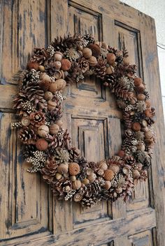 a wreath made out of pine cones and acorns is hanging on a door