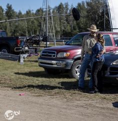 a man and woman standing in front of a truck with a camera attached to it