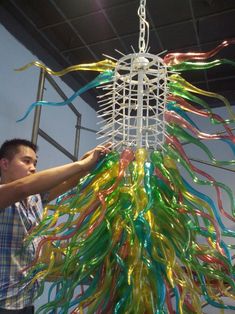 a man that is standing next to a light fixture with streamers hanging from it