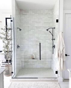 a walk in shower sitting next to a white rug and sink on top of a wooden floor