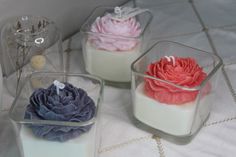 three small glass containers filled with different types of flowers on a white tableclothed surface