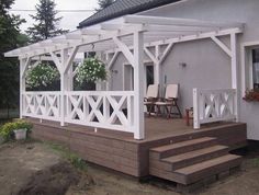 a white pergolan sitting on top of a wooden deck next to a building