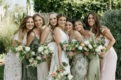 a group of women standing next to each other wearing dresses and holding bouquets in their hands