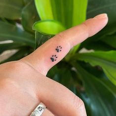 a person's hand with a tiny black dot tattoo on their left thumb and finger