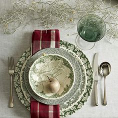 a table set with plates, silverware and an apple