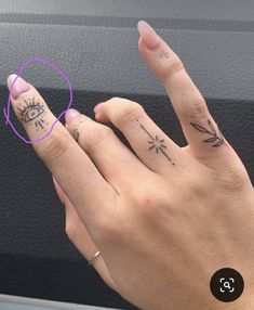 a woman's hand with two small tattoos on her fingers and the other finger