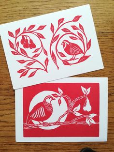 two red and white cards with birds on them sitting next to each other in front of a pair of scissors